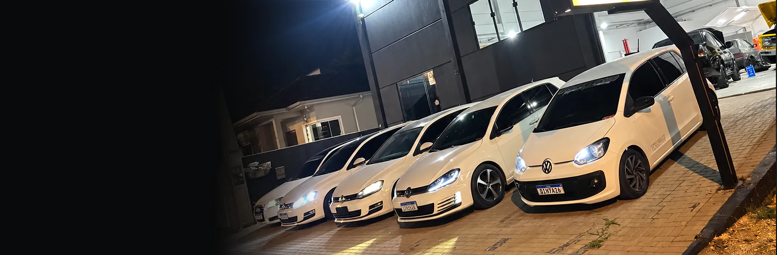Carros preparados enfileirados na frente da oficina Alemonstrinho, à noite
