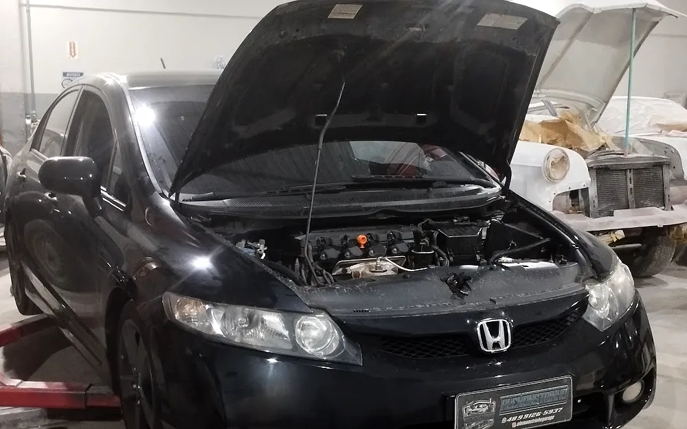 Honda Civic preto com o capô aberto na rampa da oficina